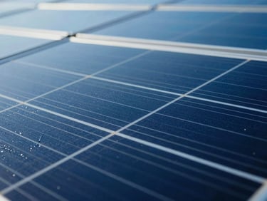 Close-up of a solar panel array reflecting a cool sky, water sheeting off the hydrophobic surface in clean lines.