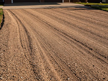The same driveway, perfectly graded, packed with crushed run gravel, sloped for runoff, warm sunlight, sharp focus