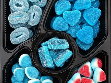 A variety of blue gummy candies including sour rings and sugar-coated hearts in a black divided tray.