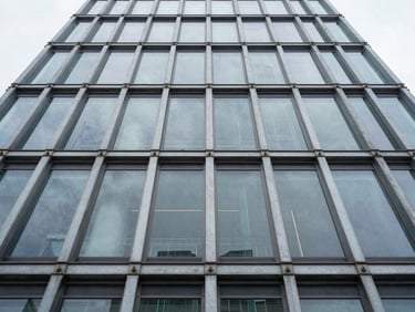 Low-angle high-contrast structural shot of a steel and glass tower facade, crisp architectural lighting, slate-gray palette.