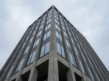 Low-angle perspective of a modern concrete and glass corporate tower, sharp overcast daylight, cool slate tones