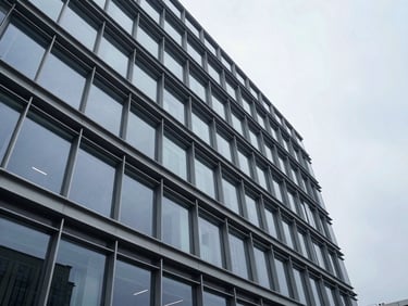 Low-angle perspective of a modern minimalist commercial office building facade, steel and glass, cool overcast day