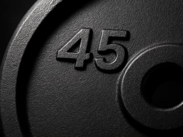 Macro shot of a high-end black urethane weight plate with clean embossed lettering, dramatic side lighting highlighting the texture, sharp focus.