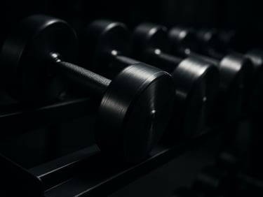 Close-up of a row of premium steel dumbbells on a dark rack, metallic reflections from a single directional light source, professional gym setting.