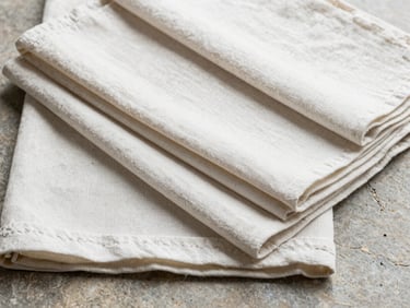 Flat lay of neatly folded cotton kitchen linens and table runners on a stone surface, industrial studio lighting, high detail texture