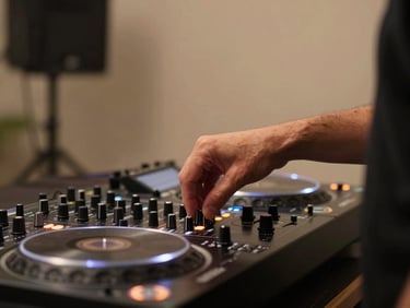 Candid side-profile of a focused DJ adjusting a dial on a high-end rotary mixer, warm ambient lighting, soft focus background
