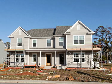 Exterior shot of a residential property undergoing significant improvement, scaffolding visible, organized site, clear South Carolina sky.