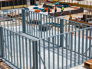 Detailed close-up of new structural steel framing on an active job site, workers in safety gear, organized materials, bright natural South Carolina daylight.
