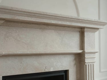 Close-up of a massive honed limestone fireplace surround catching diffused overcast light, highlighting natural cream textures.