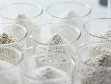 Close-up of various fine chemical powders in laboratory beakers, distinct textures, bright studio lighting, technical focus, 35mm