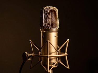 Close-up of a professional talk-show microphone under warm gold spotlight, dark background, cinematic, 35mm