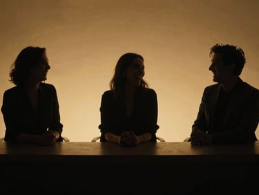Moody silhouette of talk show hosts laughing behind a desk, warm golden backlight, deep matte black shadows, cinematic