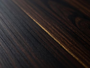 Macro close-up of dark walnut wood grain with subtle gold leaf inlaid in the crevices, warm side lighting