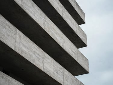 Abstract architectural lines of a concrete building under overcast skies, soft-focus composition, high negative space.
