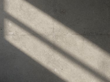 Soft abstract play of light and shadow on a light warm gray concrete wall, quiet and atmospheric