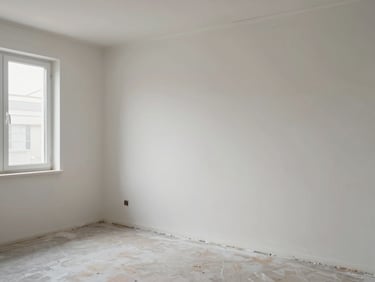 Wide shot of an empty residential room at the surface preparation stage — base coat applied, walls bare of paint, natural diffuse daylight from a window showing the even coverage of the preparatory plaster layer; no tools staged, no people posed, only the wall as evidence