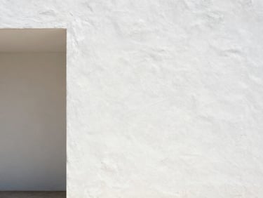 Architectural interior with soft natural light illuminating a white plaster wall, minimal furniture