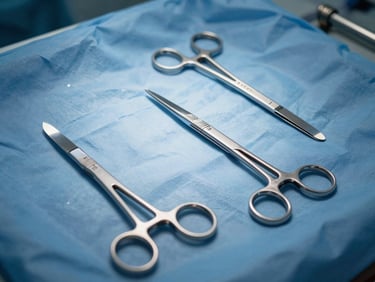 Close-up of stainless steel surgical instruments laid flat on a sterile blue drape, scalpels and forceps in precise arrangement, clinical overhead lighting, no hands