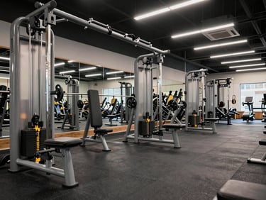 Functional training zone in a commercial gym showing cable machines, suspension rigs, and rubber flooring under bright overhead lighting, empty floor mid-setup