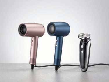 Professional ionic hair dryer and a premium electric shaver arranged neatly on a cool grey surface, high-key studio light.
