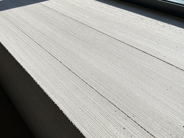 Close-up of a textured sustainable building material, like recycled timber or polished concrete, with sharp natural daylight creating deep shadows, wide-angle lens, 35mm