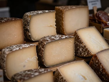 Macro shot of artisanal cheeses and charcuterie on a market shelf, rich high-contrast earth tones, soft shadows