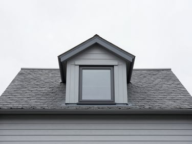 Straight-on exterior view of a modern dormer loft conversion with clean grey cladding, slate roofline, bright overcast daylight, 35mm