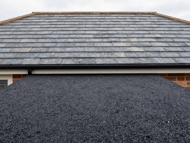 Close-up architectural shot of a newly laid resin-bound driveway leading to a freshly tiled slate roof in Sale, sharp focus, neutral desaturated tones