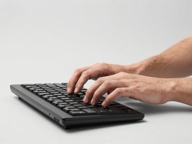 Professional portrait of a man typing on a high-end keyboard, clean studio lighting, light gray background, sharp details, high-contrast, 85mm lens