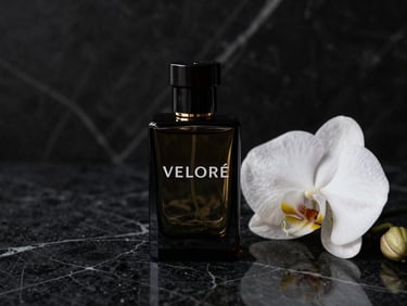 Una botella de perfume de vidrio oscuro de VELORÉ sobre una mesa de mármol negro con una orquídea blanca en primer plano, iluminación cinematográfica lateral, 35mm