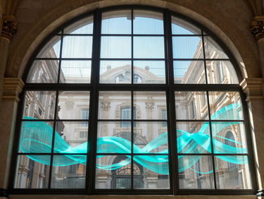 Symmetrical daytime shot of a monumental arched glass window on Via del Corso, Rome. The flexible LED film is active with bright cyan abstract fluid graphics, sunlight streaming through the transparent mesh into the luxury interior.