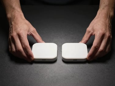 Hands interacting with a physical product comparison — two items side by side on a dark matte surface under a single focused studio strobe, one hand gently touching the edge of each product, natural skin tone, neutral background, no labels