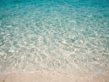 Crystal clear turquoise water of Capo Vaticano, white sandy seabed visible through the water, sun-drenched Mediterranean light