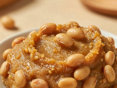 Close-up of textured golden-brown Doenjang soybean paste, visible whole beans, rustic sunlit background, shallow depth of field, 35mm.