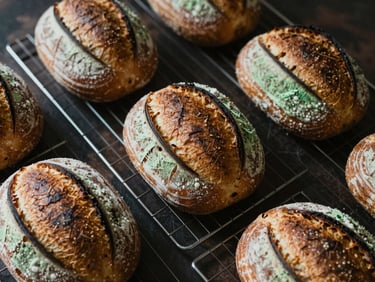 Overhead shot of freshly baked sourdough bread loaves cooling on a wire rack in a cozy bakery, warm morning light, 35mm