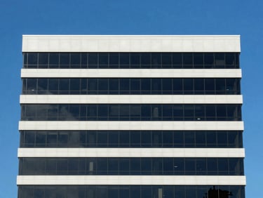 Crisp architectural shot of a five-story commercial office building in Tampa, glass facade reflecting deep blue sky, bright daylight