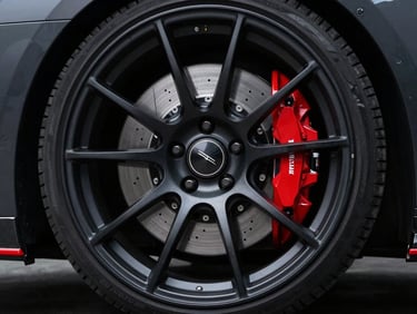 Low-angle shot of a custom black-dipped wheel and red brake caliper, dramatic studio lighting, 50mm