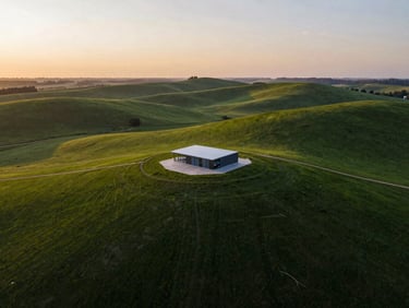 Sweeping drone shot of a lush rolling green land lot at sunset, soft natural light, 35mm photography.