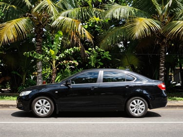 Clean black sedan on a paved road in Nicaragua, bright daylight, tropical trees in background.