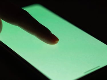 Extreme close-up of a finger interacting with a sleek Android screen, showing slight motion blur and bright green screen glow, moody dark-room lighting