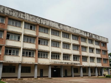 Straight-on exterior of a large institutional education building in Vijayawada — wide setback, multi-storey block, ground-floor corridor windows, concrete and brick facade, flat diffused daylight