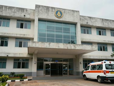 Exterior entrance of a purpose-built hospital building in Vijayawada — wide concrete facade, porte-cochere canopy, ground-floor reception windows, even overcast daylight, empty ambulance bay in foreground