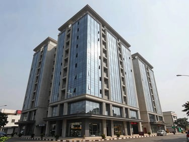 Environmental exterior shot of a newly completed multi-storey commercial investment building in Vijayawada — full-height glass and concrete structure, ground-floor retail podium, street-level pavement, overcast north-facing daylight