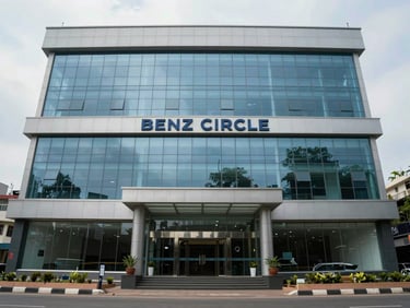 Straight-on exterior shot of a mid-rise office building in Benz Circle, Vijayawada — clean glass entrance, corporate signage band above ground floor, overcast even daylight, street pavement visible at bottom edge