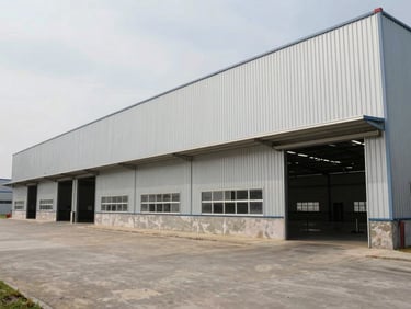 Exterior of a multi-bay industrial warehouse in Auto Nagar, corrugated steel facade, wide concrete apron in front, overcast daylight, environmental wide shot showing full building width