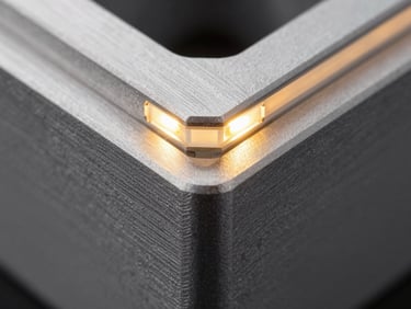 Close-up macro shot of a machined aluminum corner, showing the integrated LED light bar glowing a soft amber status color, sharp highlights on the matte metal surface.