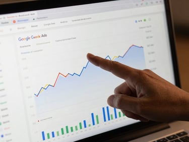 Close-up of a Google Ads performance dashboard on screen mid-analysis, a hand pointing at a conversion rate line graph, clean studio lighting, screen fully legible, no glare