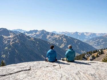 Vast sunlit mountain ranges in the Pacific Northwest, high-key crisp natural daylight, clean technical gear layout on a granite ledge in the foreground, wide-angle lens, bright alpine colors.