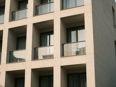Architectural detail of a modern, clean building facade, emphasizing structure and design, soft daylight, muted earth tones, warm editorial photography.
