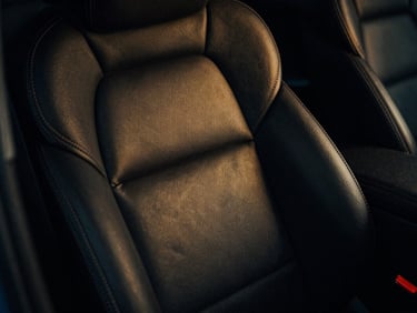 High-contrast image of a luxury car interior detail, low-key lighting, rich textures, subtle gold reflections.